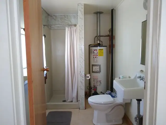 Atlanta Cabin β A bathroom with toilet, sink, water heater, and shower.