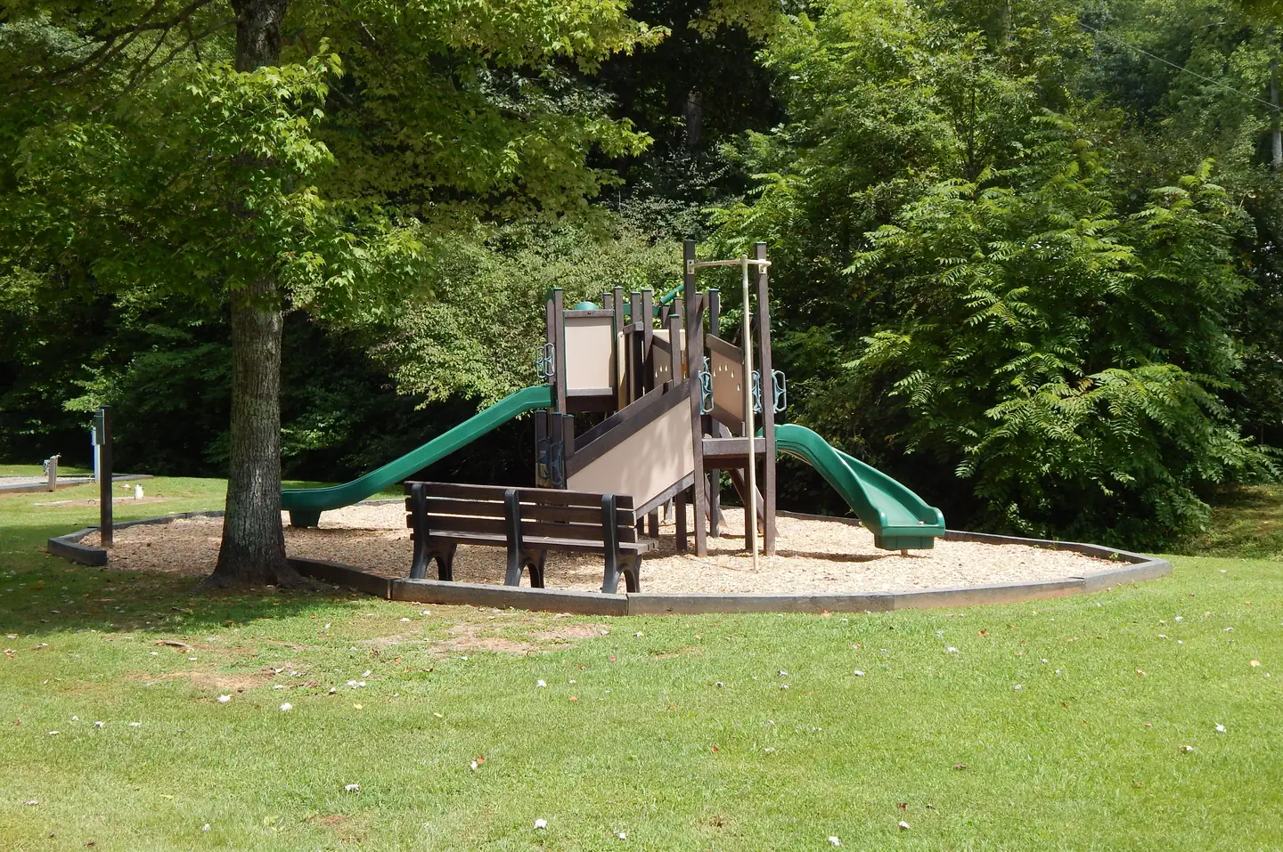 Salthouse Branch Campground — A small playground nestled in the trees and surrounded by manicured grass.