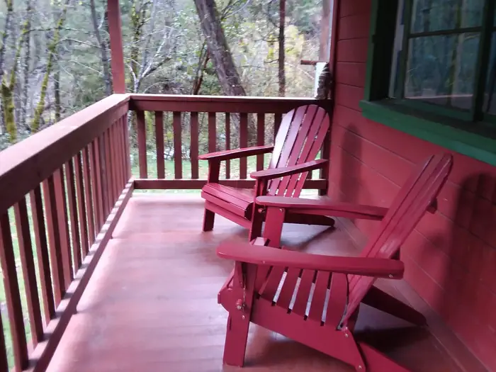 Forest Glen Guard Station — Front porch and two red Adirondack of red cabin.