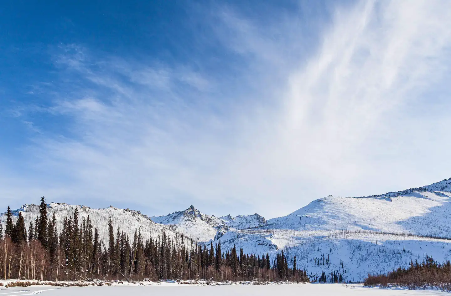 White Mountains National Recreation Area - Alaska Cabins — A frozen river and mountains under a blue sky