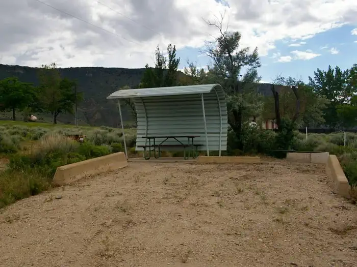 Lucerne Campground - Ashley National Forest — Picnic table with a shelter covering one side and over head and parking in the front.
