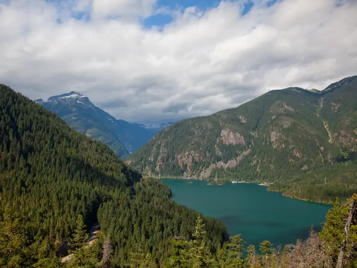 Colonial Creek North Campground — A view of Diablo Lake, surrounded by forested mountains and blue sky with clouds.