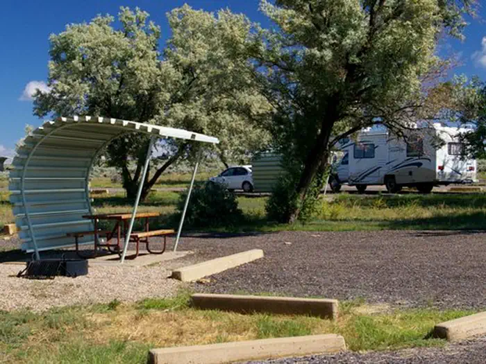 Buckboard Crossing — Campsite with a picnic table and fire pit. Forest users are at other campsites in the background.