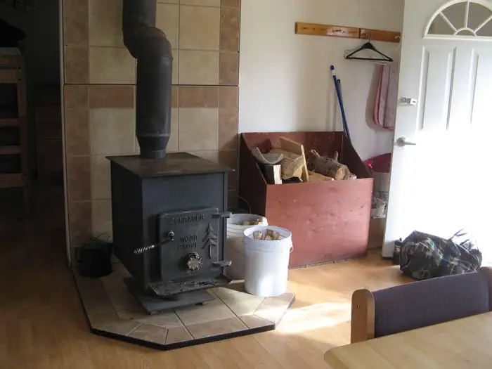 Calf Creek Cabin — A black iron woodstove at the entrance to a cabin