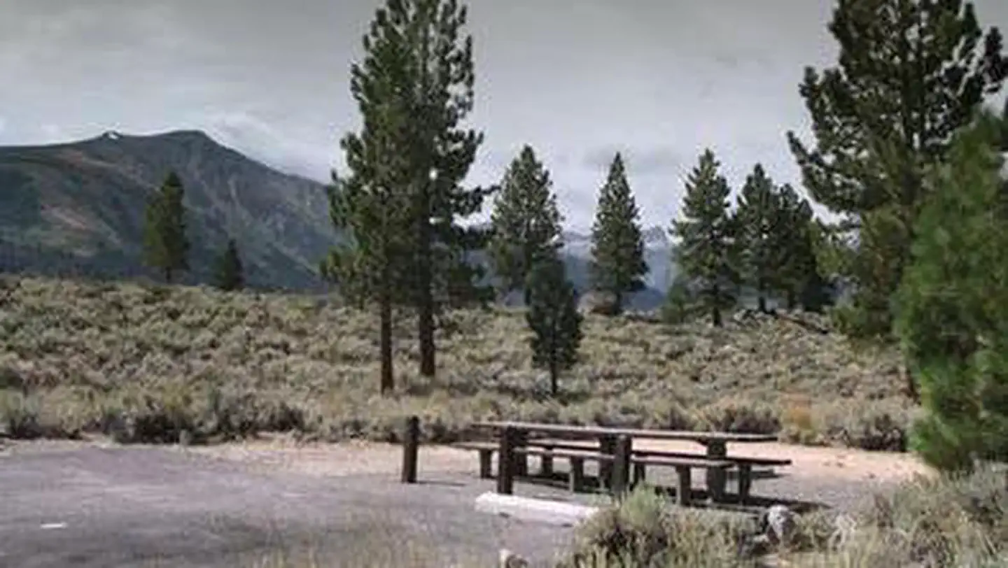 Paha — A campsite and picnic table featured with mountains and trees in the distance.