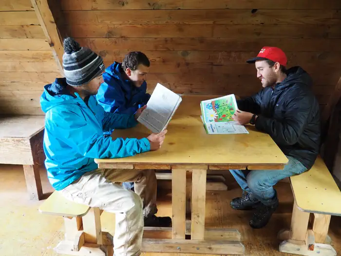 Berg Bay Cabin β Three people at a wooden table in a Berg Bay cabin
