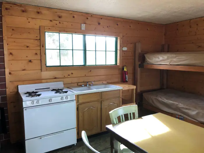Jones Corral Guard Station β Cabin interior showing gas range, bunkbeds, table and dry sink