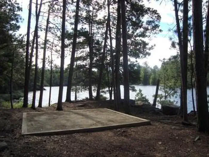 Voyageurs National Park Campsites — Square tent pad surrounded by trees and a scenic lake.