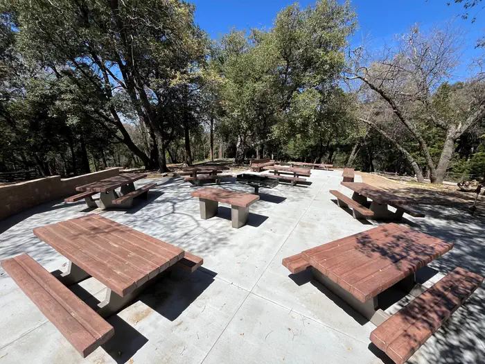 Crestline Group Campground β Group area, pictured 6 picnic tables, one kitchen table, large fire grill, three benches, and group fire ring.
