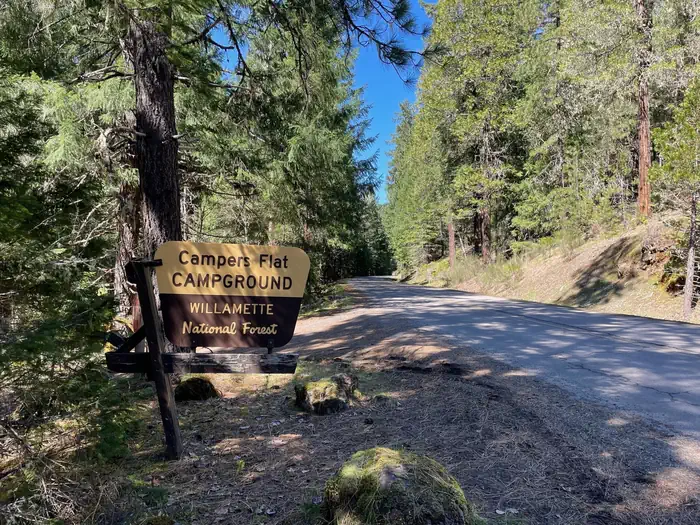 Campers Flat Campground — A brown and cream sign on a wooden stand. The sign reads "Campers Flat Campground".