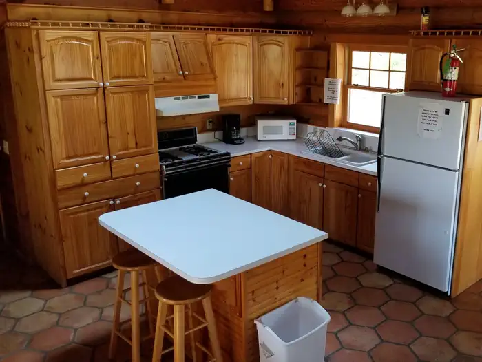 Grouse Valley — View of the kitchen in the Hillside Cabin with wood cabinents refrig, stove, and island bar with 2 stools