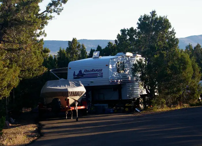 Deer Run Campground — RV Trailer and boat parked in a camping site spur.