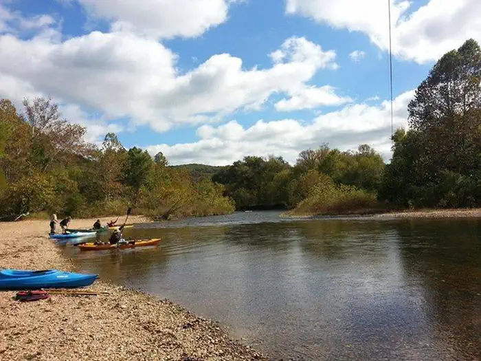 Pulltite Campground — Kayaks on the water and beach at Pulltite under a blue sky with puffy white clouds.