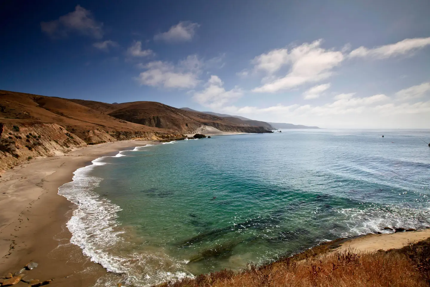 Santa Rosa Island Backcountry Beach Camping — Sandy beach with ocean and small waves and steep coastal bluffs covered in grass. 