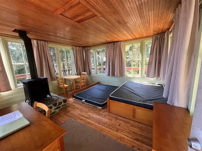 Timber Butte Cabin — Inside of cabin with trundle bed, desk, table, and propane heater.