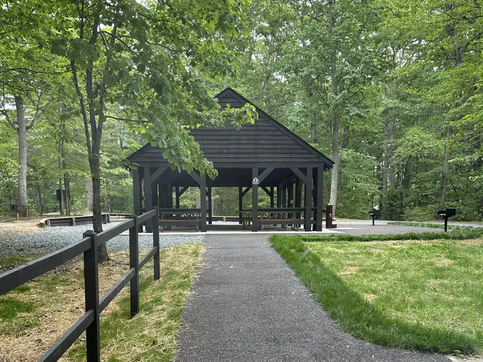 Telegraph Picnic Pavilion — Paved walkway leading to a wooden roofed and paved picnic pavilion shaded by trees