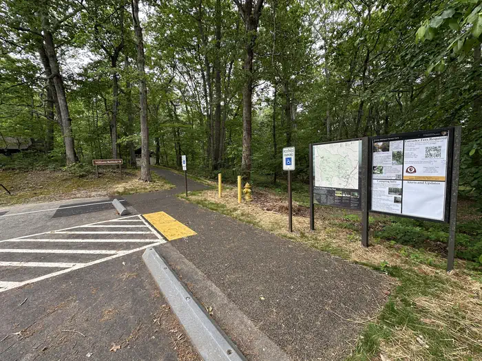 Telegraph Picnic Pavilion — Handicapped parking and a paved walkway beside information signs in a forest