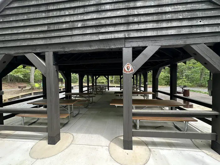 Telegraph Picnic Pavilion — Eight picnic tables sit on a concrete pad under a wooden open sided picnic shelter