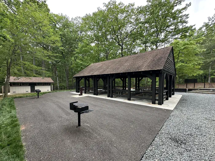 Telegraph Picnic Pavilion — Opened sided, roofed picnic pavilion in the forest near a flat surface with two standing grills with a restroom building nearby