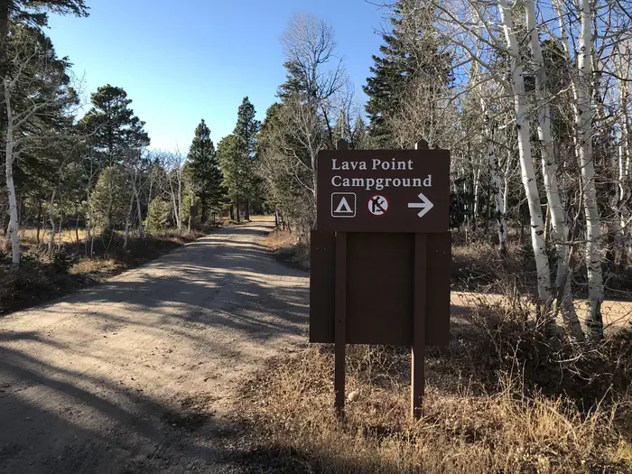 Lava Point Campground — Sign alongside forested dirt road directs campers to the campground entrance.