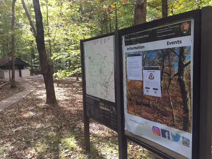 Turkey Run Ridge Group — Bulletin board and map sign in the forest near a sidewalk and building in a campground