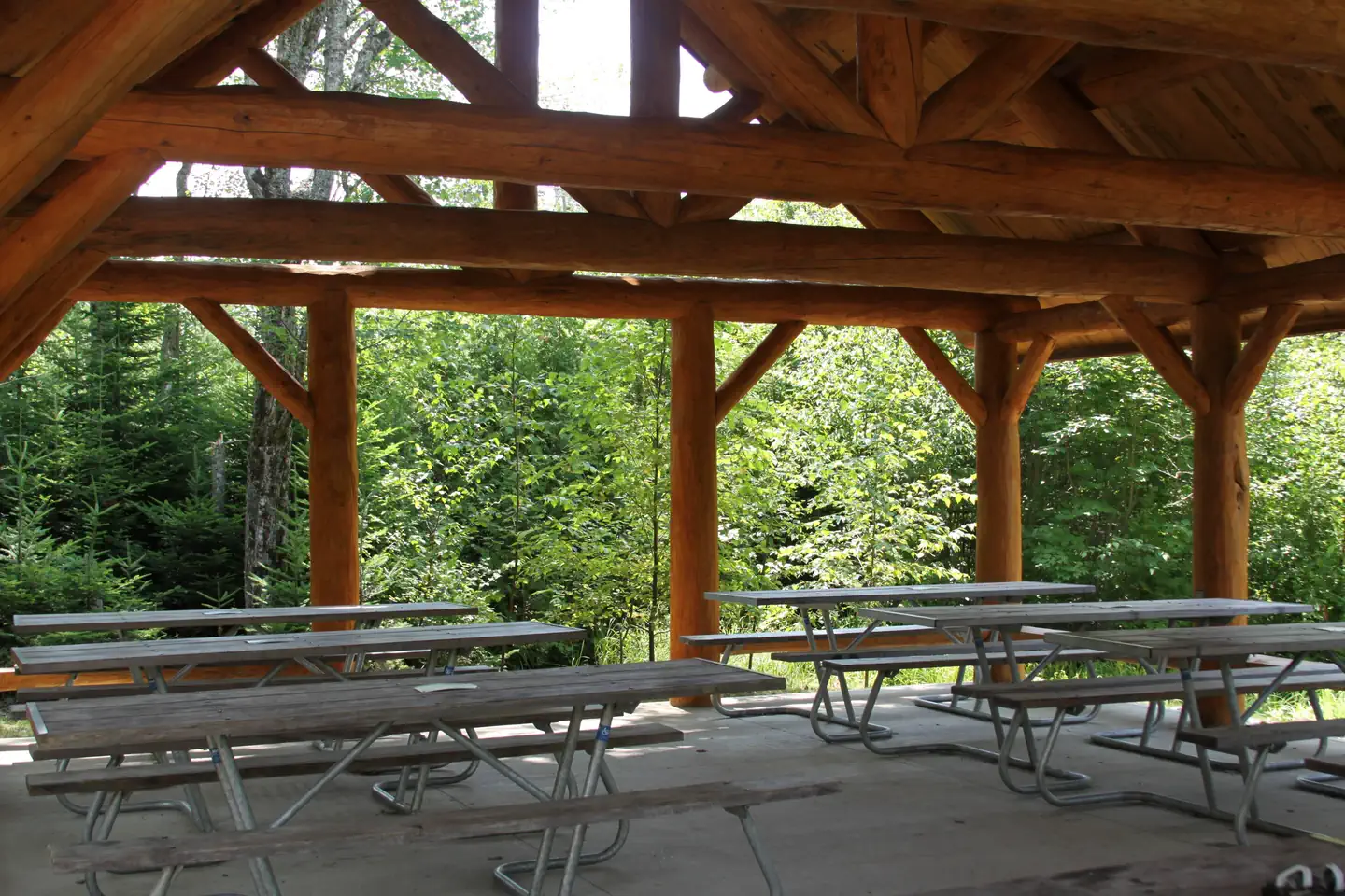 Schoodic Woods Campground — Interior view of log cabin style picnic pavilion with accessible picnic tables.