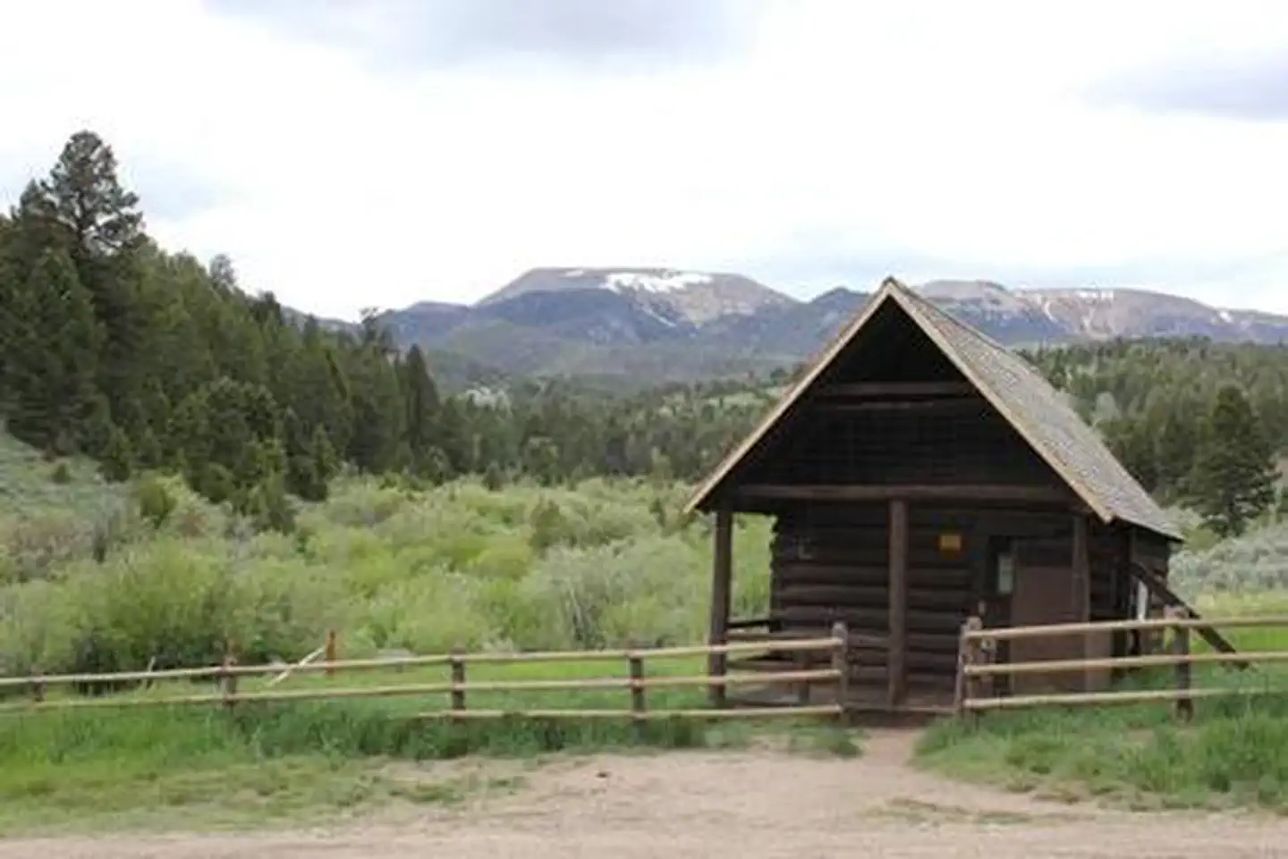 Hells Canyon Guard Station — Brown forest service cabin surrounded by green trees and rolling hills