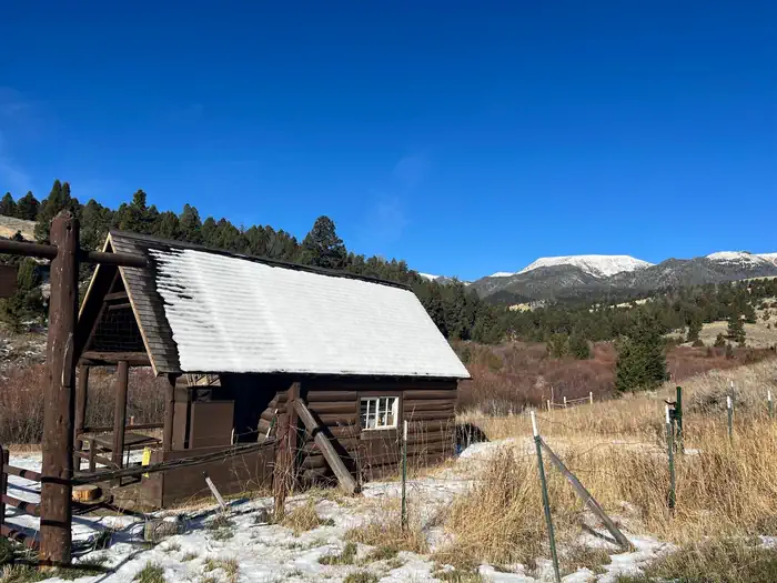 Hells Canyon Guard Station — Brown cabin surrounded by green trees and rolling landscape