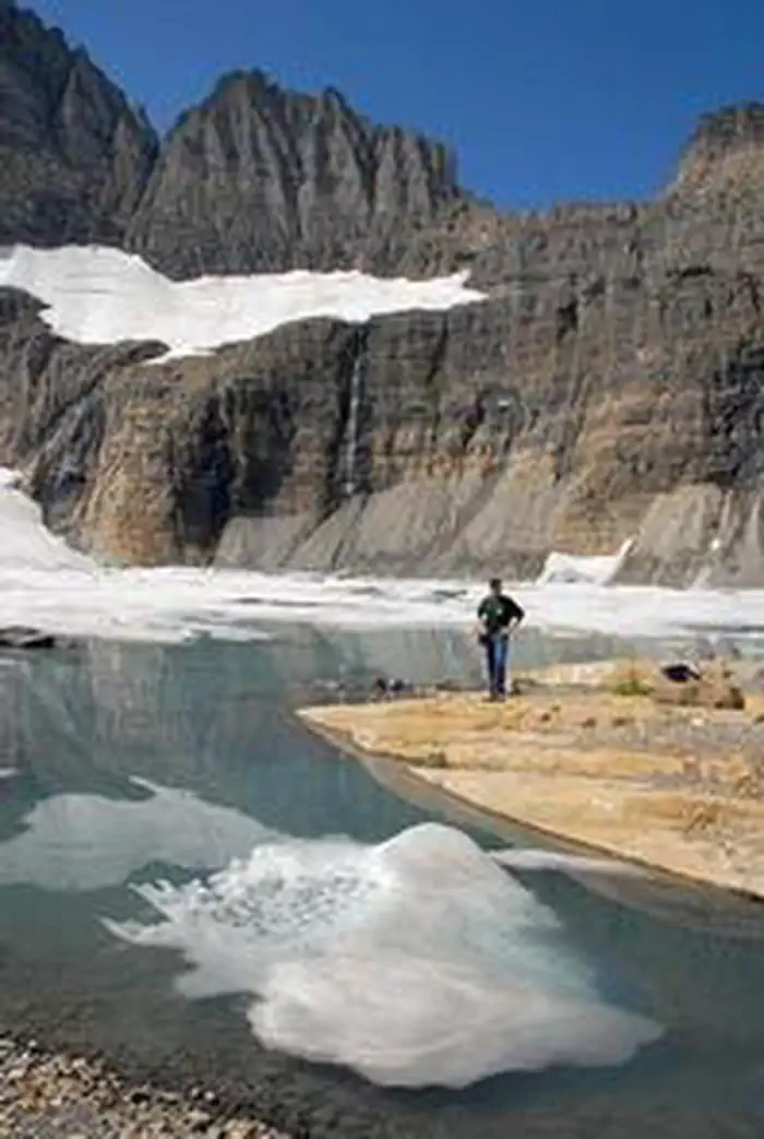 Many Glacier Campground — A man views rock cliffs above an alpine lake near Many Glacier