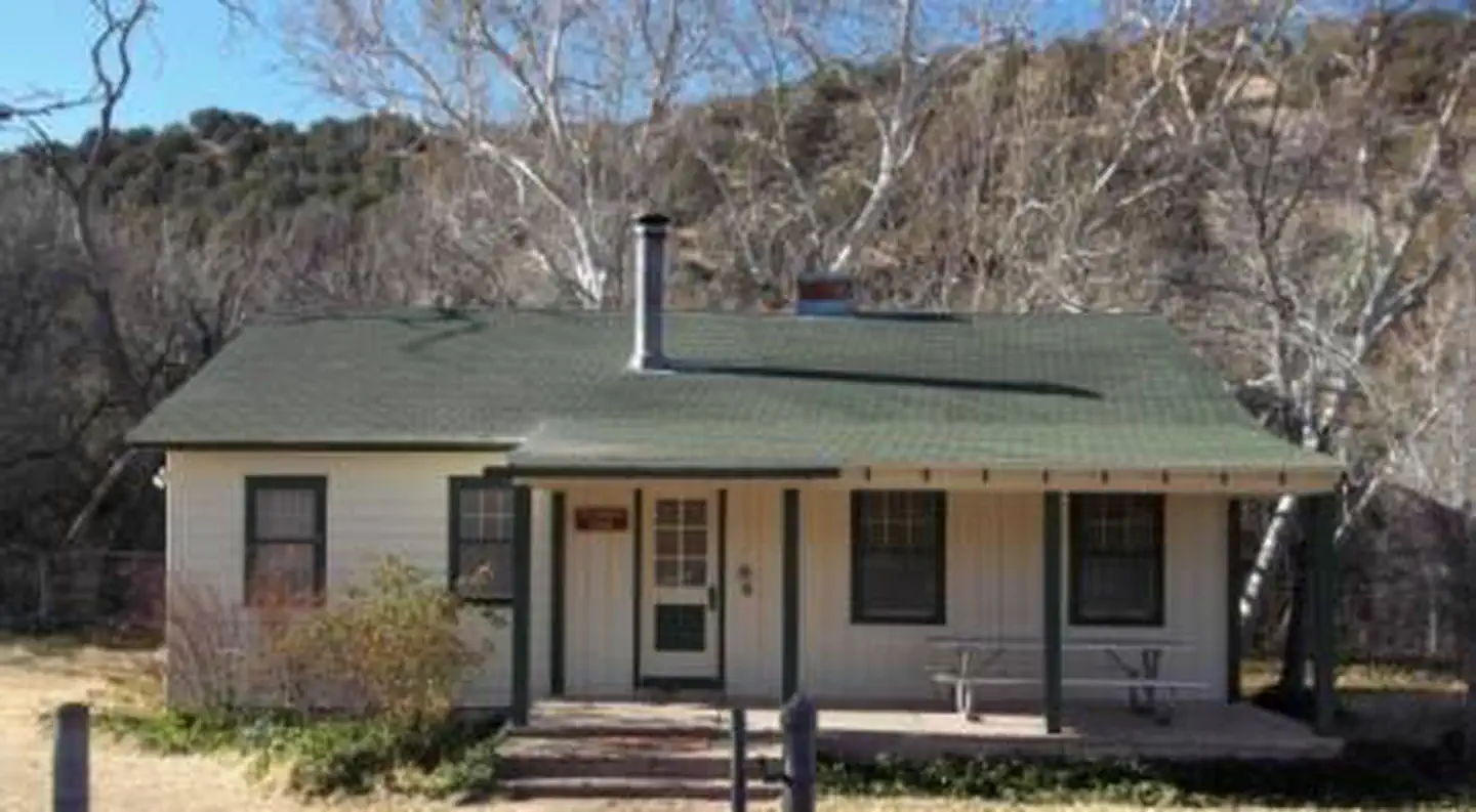 Sycamore Cabin β White exterior of Sycamore Cabin with a green roof, three stairs of different depths to porch with picnic table to right of door.