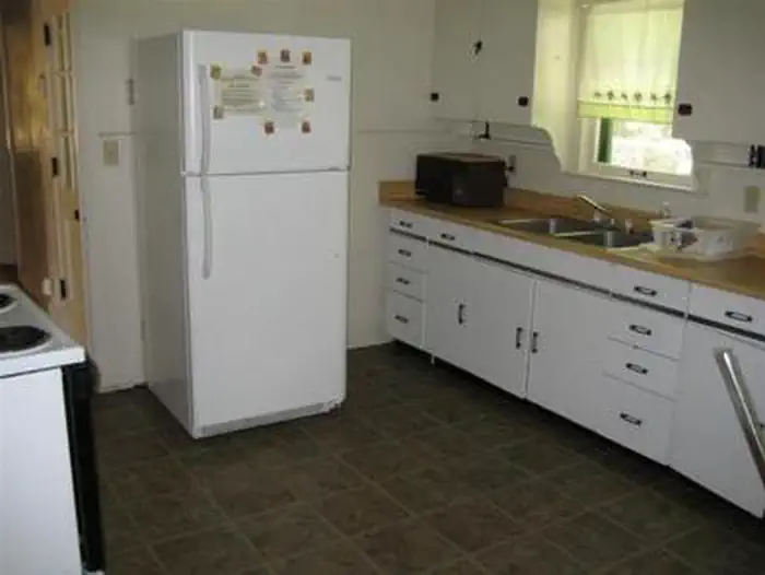 Sycamore Cabin β Kitchen with full size fridge with upper freezer, microwave next to metal sink with dish rack across from electric stove.