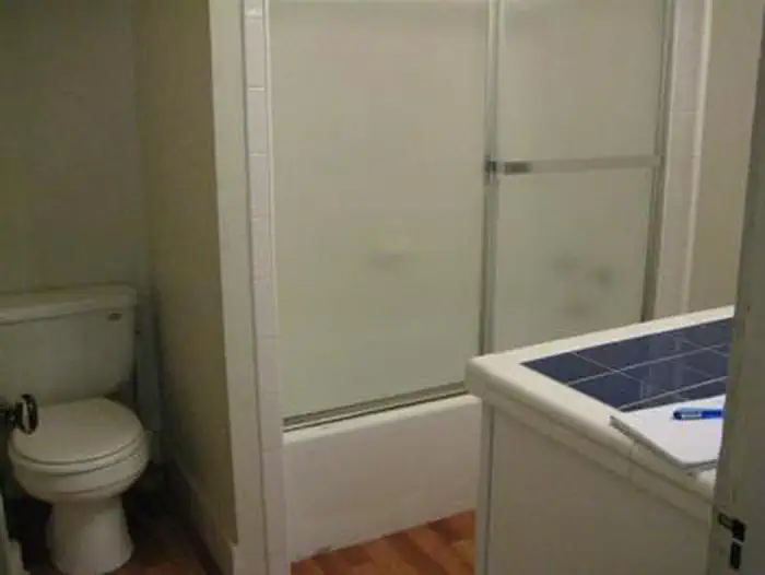 Sycamore Cabin β Cabin bathroom with tub shower combination with glass door, toilet and single bowl sink. Tight for wheelchair access.