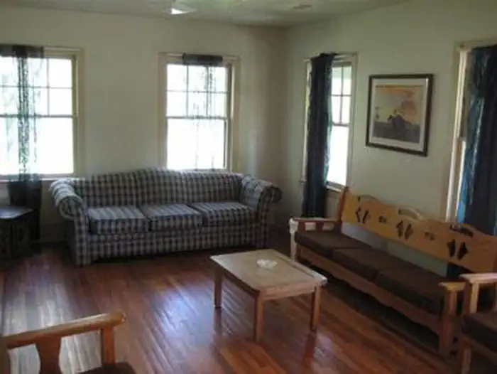 Sycamore Cabin β Cabin living room with couch, three person bench, coffee table and chairs.