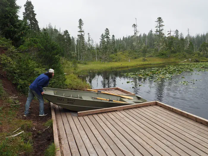 Middle Ridge Cabin — Person pushing skiff into lake from platform