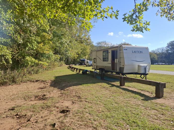 Ozark — A white RV sits on a green lawn at a campsite in Ozark Campground.