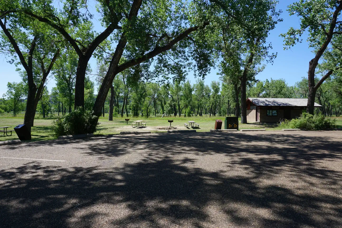 Juniper Campground Group Site — Parking area with the restroom and picnic tables in the distance