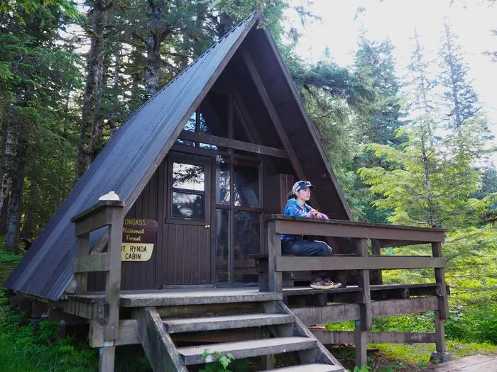 Mount Rynda Cabin — Person looking at scenery from railing of Mount Rynda Cabin exterior A Frame cabin