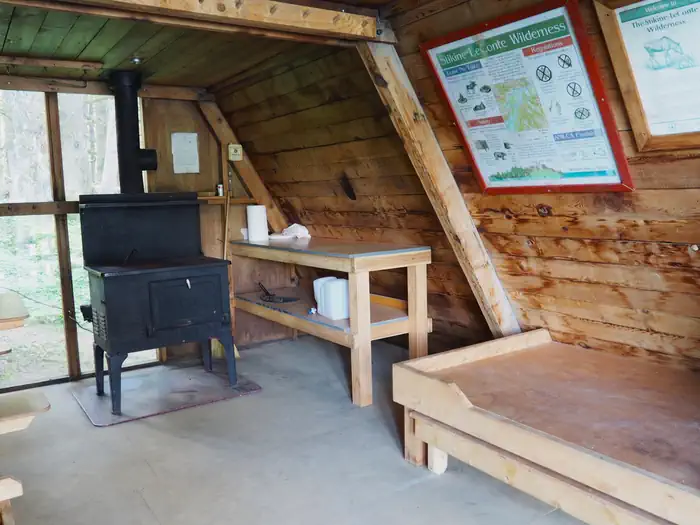Mount Rynda Cabin — Mount Rynda Cabin interior with wood cabinet and bed with stove