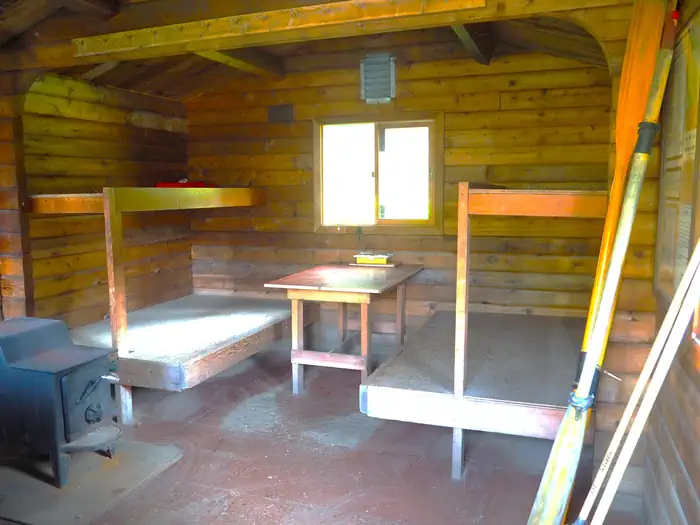 Marten Lake Cabin β Marten Lake Cabin interior showing 4 wood bunkbeds, small table and stove with oars leaning against wall