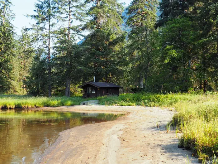 Marten Lake Cabin β Marten Lake Cabin with trees surrounding it and water in front with a small boat