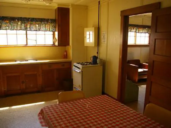 Deer Park Cabin β A kitchen with a table, stove, sink, and countertops.