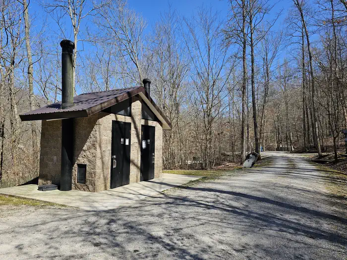 Alum Ford Campground — Vault toilet facility sits in gravel parking lot of campground.