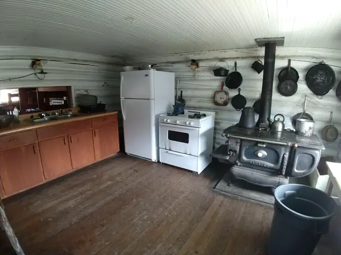 Stone Cellar Guard Station β Kitchen with classic wood stove oven, modern oven and refrigerator