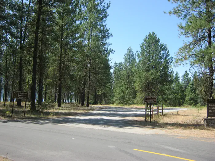 EVANS GROUP CAMP — The photo shows a gravel parking area in a pine forest with a wooden fence and a sign reading “Group Site”