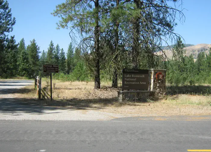 EVANS GROUP CAMP — The photo shows a stone‑based National Park Service entrance sign for Lake Roosevelt National Recreation Area (Evans) standing among tall pines.