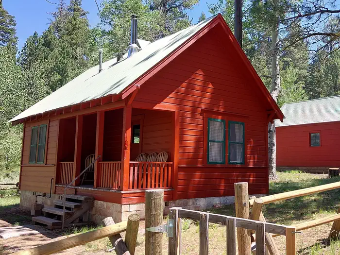 Patterson Guard Station — A sunny day illuminates Patterson Guard Station. The bright red color of the Guard Station contrasts the green conifer trees behind it. 