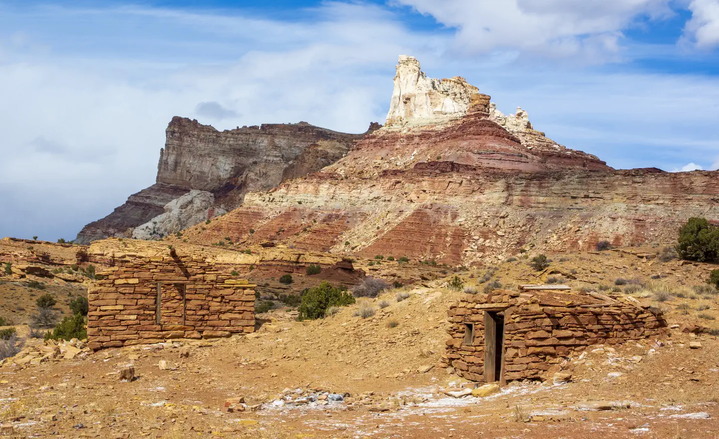 Temple Mountain Townsite Campground — Stone cabin ruins with a sandstone butte in the background