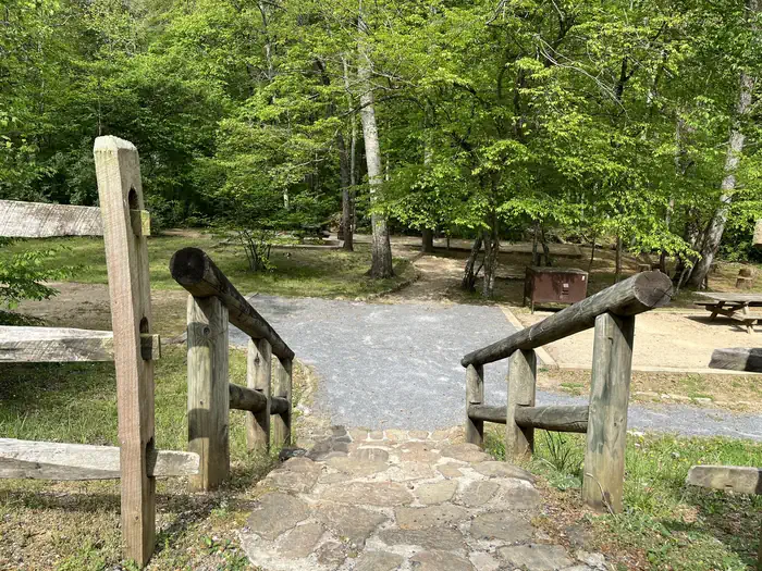 CAVE MOUNTAIN LAKE GROUP CAMP — Wooden hand rail and stone steps leading to gravel tent sites surrounded by trees