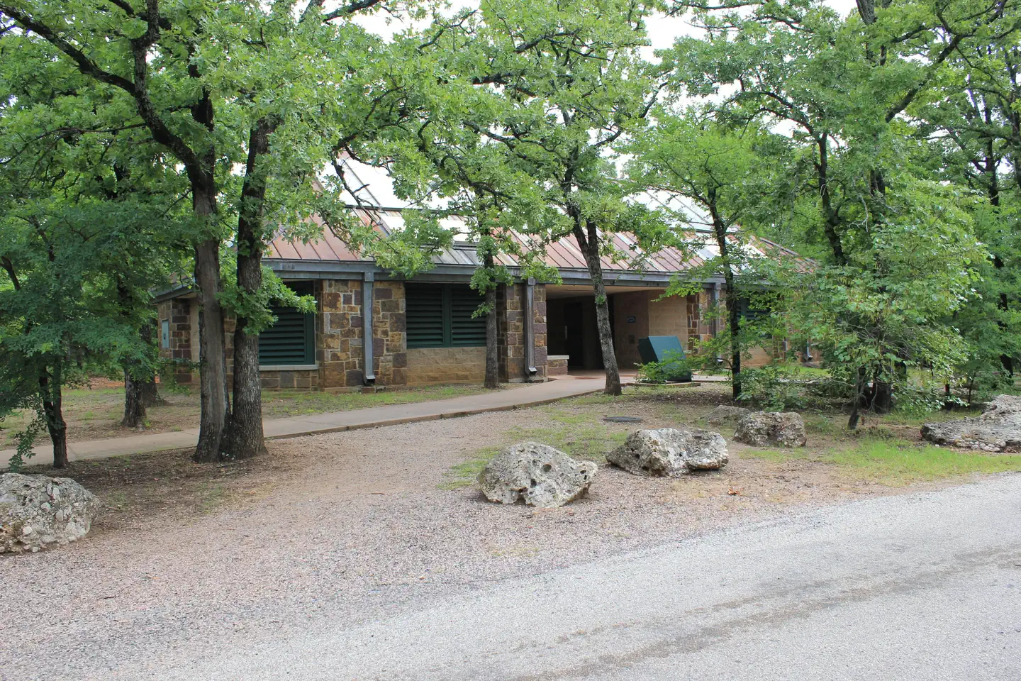 Buckhorn Campground (Chickasaw) — Brick building left of roadway in D Loop surrounded by trees.
