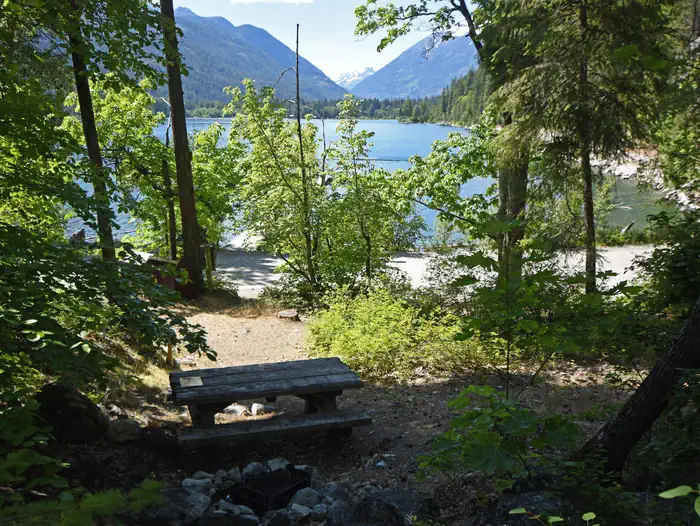 Purple Point Campground — Picnic table with trees, lake, and mountains in the background.